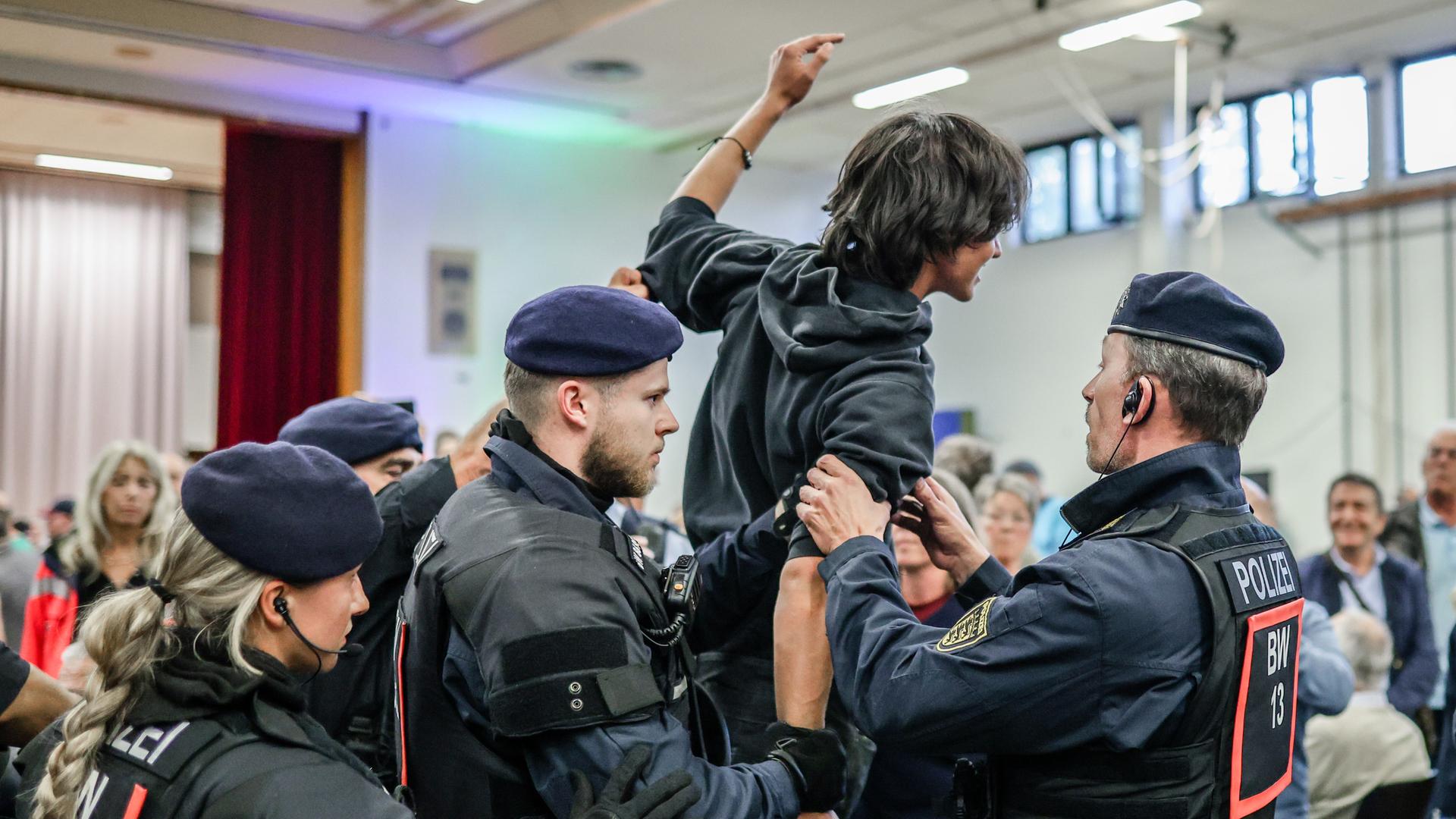 Polizeibeamte führen einen Mann aus der Halle, der die Diskussionsrunde gestört hatte.