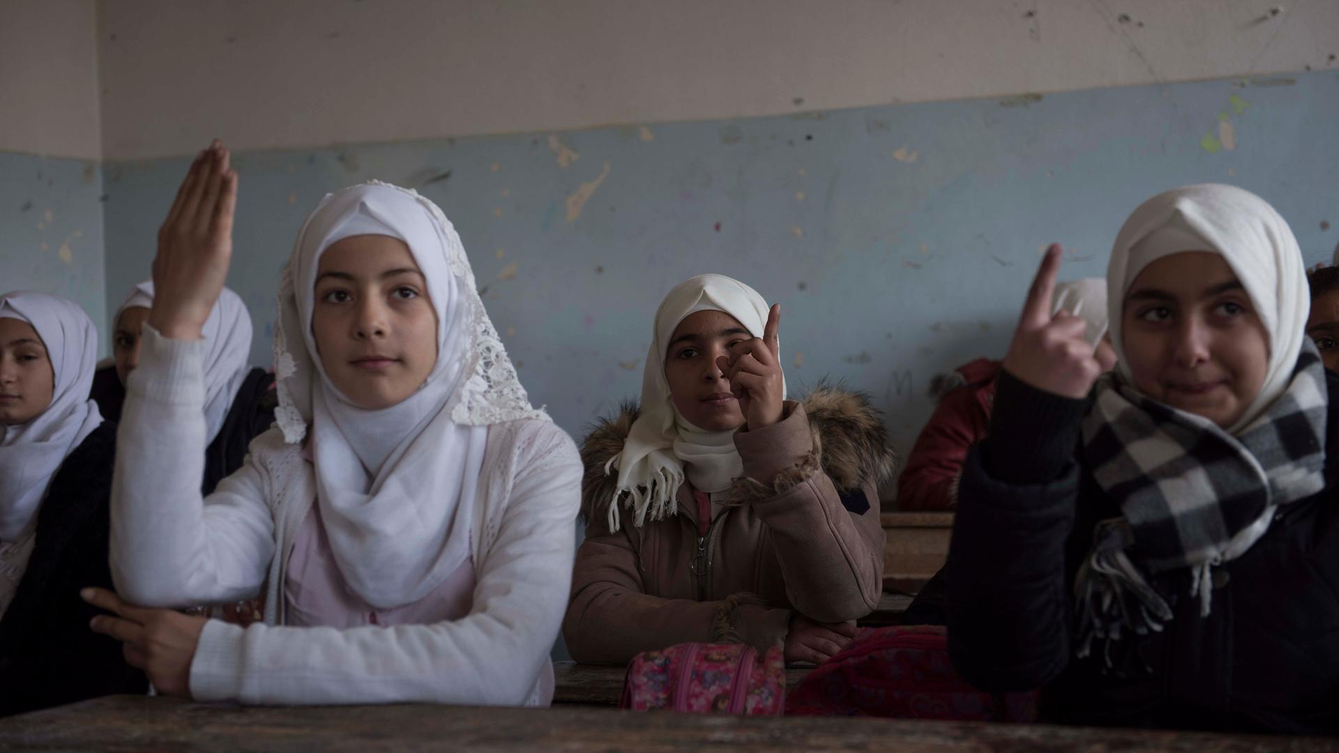 Mädchen in einer Schule in Al -Mliha, Syrien. Mehrere Mädchen melden sich.