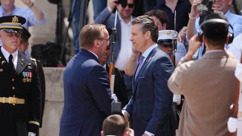Pistorius wird von seinem US-Amtskollegen Hegseth empfangen. Sie stehen sich gegenüber und begrüßen sich mit Handschlag.