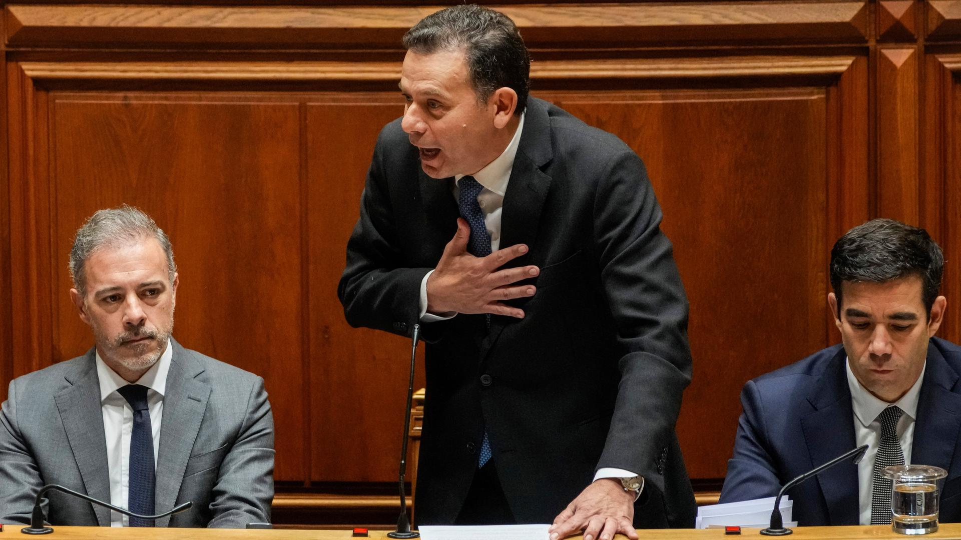 Luis Montenegro hält mit emotionaler Körperhaltung eine Rede im Parlament, neben ihm sind weitere Politiker sitzend zu sehen.