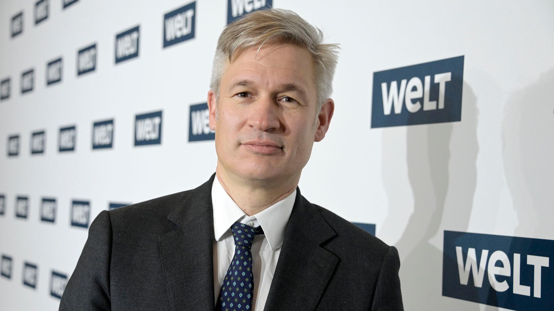 Ulf Poschardt steht im Axel-Springer-Haus. Hinter ihm stehen mehrere Logos mit der Aufschrift "Welt". Ulf Poschardt steht im Axel-Springer-Haus. Hinter ihm stehen mehrere Logos mit der Aufschrift "Welt".
