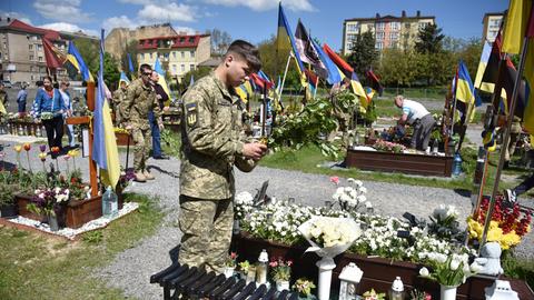 Ein Soldat legt Blumen ab Grab eines gefallenen Kameraden nieder.