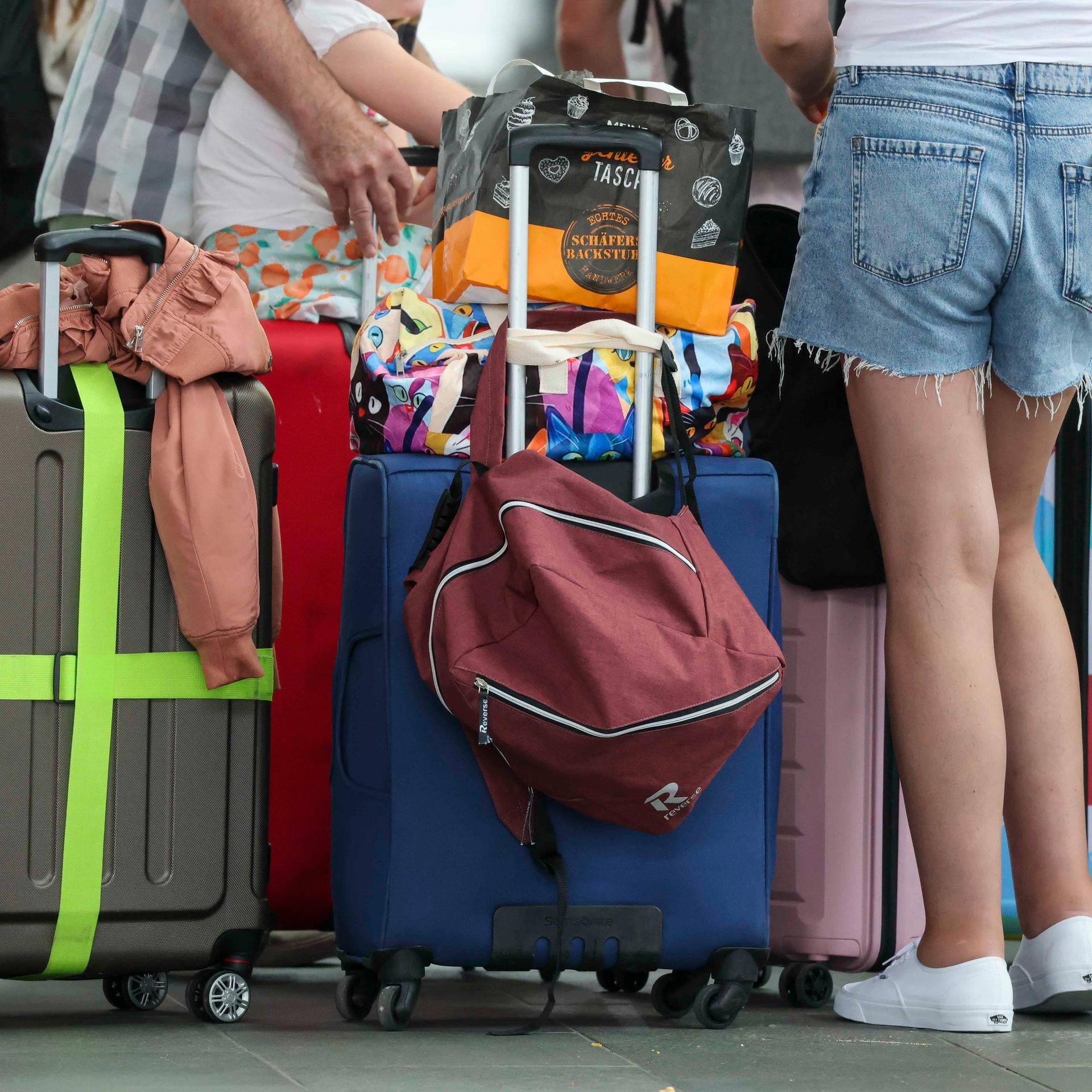 Flugreisende warten mit ihren Koffern am Check-in im Flughafen Leipzig/Halle.