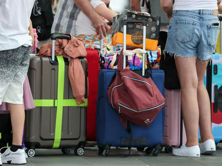 Flugreisende warten mit ihren Koffern am Check-In im Flughafen Leipzig-Halle.