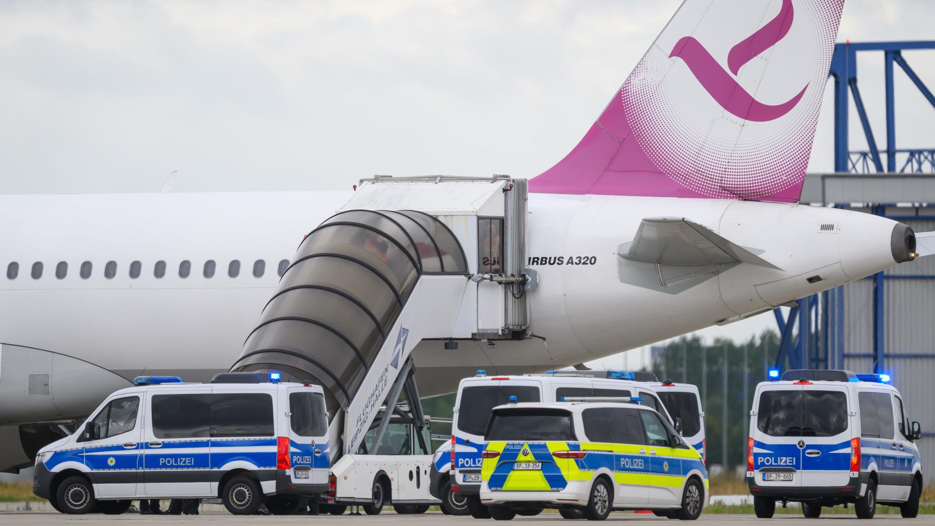 Fünf Polizeifahrzeuge fahren auf dem Flughafen Leipzig/Halle an einem Airbus vor.