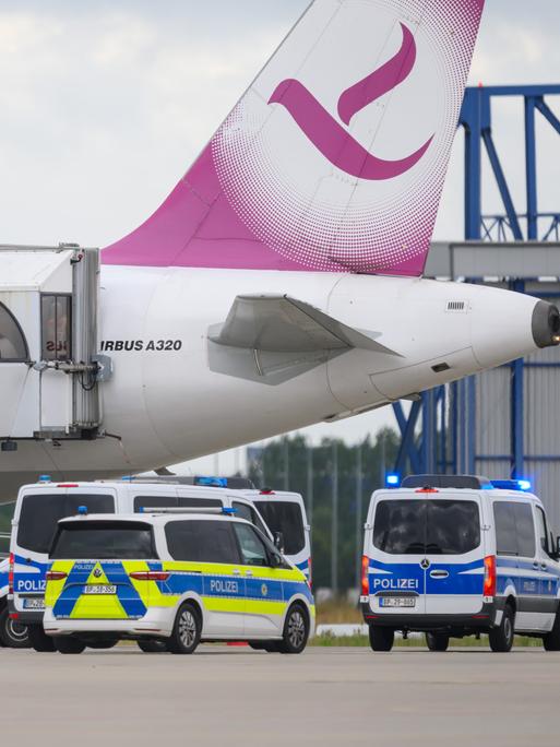 Fünf Polizeifahrzeuge fahren auf dem Flughafen Leipzig/Halle an einem Airbus vor.