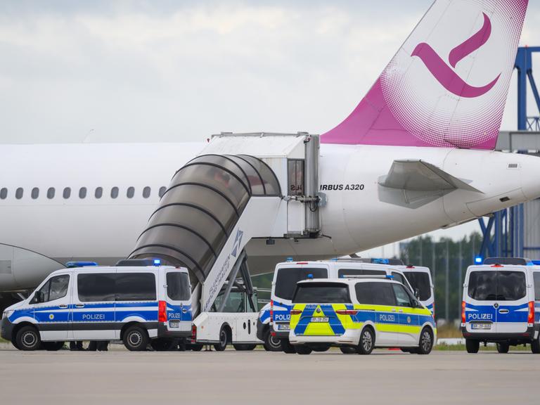 Fünf Polizeifahrzeuge fahren auf dem Flughafen Leipzig/Halle an einem Airbus vor.