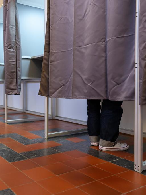 Ein Mann steht in einer Wahlkabine im Neuen Rathaus der Stadt Leipzig.