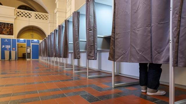 Ein Mann steht in einer Wahlkabine im Neuen Rathaus der Stadt Leipzig.