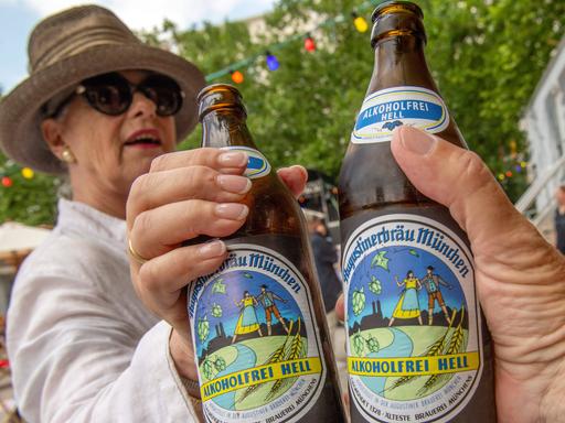 Zwei Personen stoßen in Münchens erstem akoholfreien Biergarten mit alkoholfreiem Augustiner Helles an.