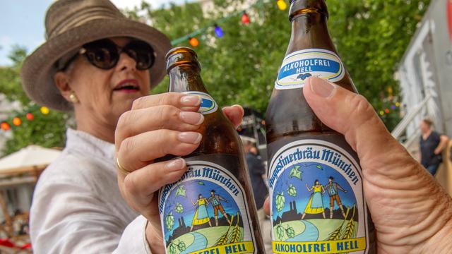 Zwei Personen stoßen in Münchens erstem akoholfreien Biergarten mit alkoholfreiem Augustiner Helles an.
