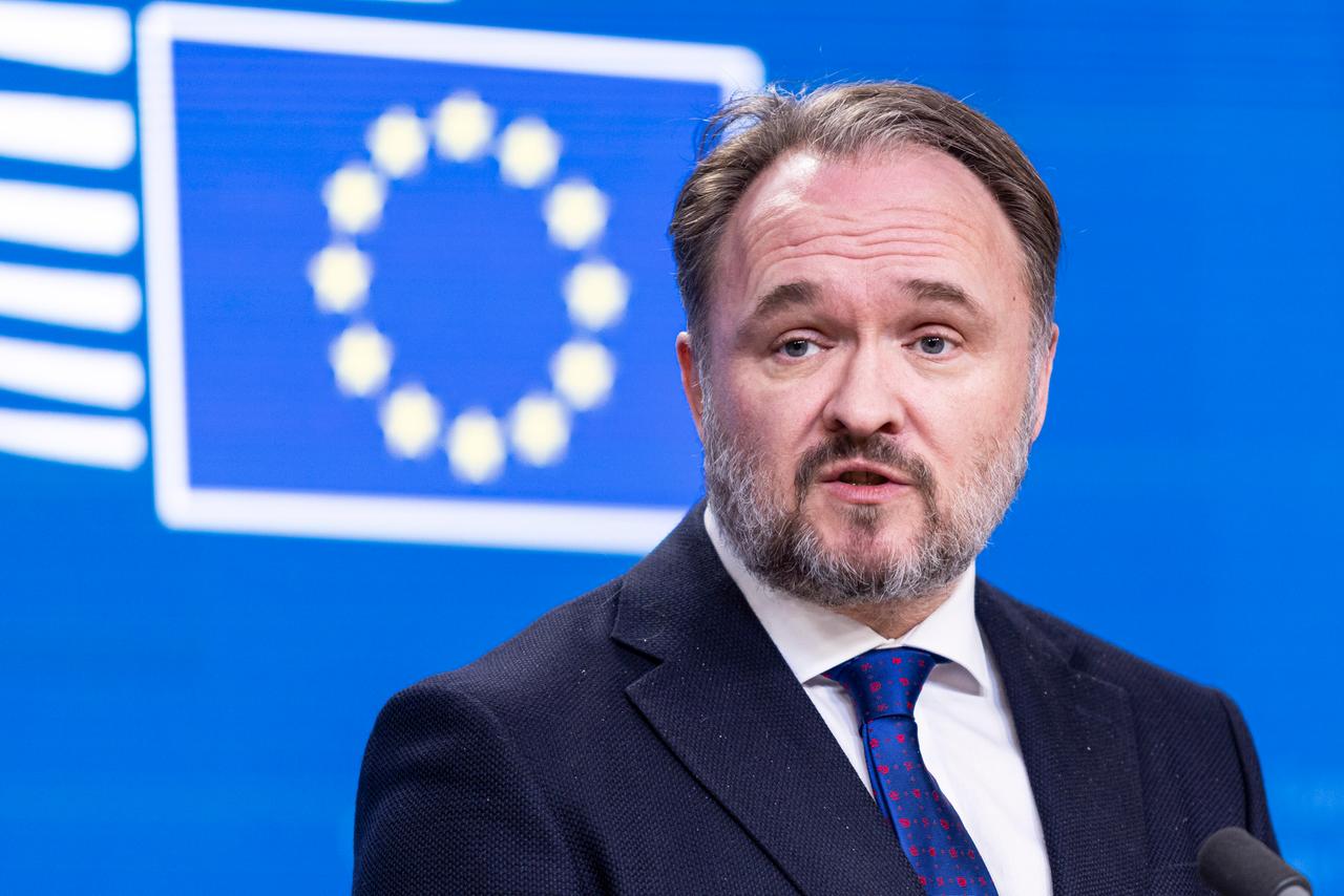 Dan Jorgensen steht vor einem blauen Hintergrund mit der Flagge der EU.