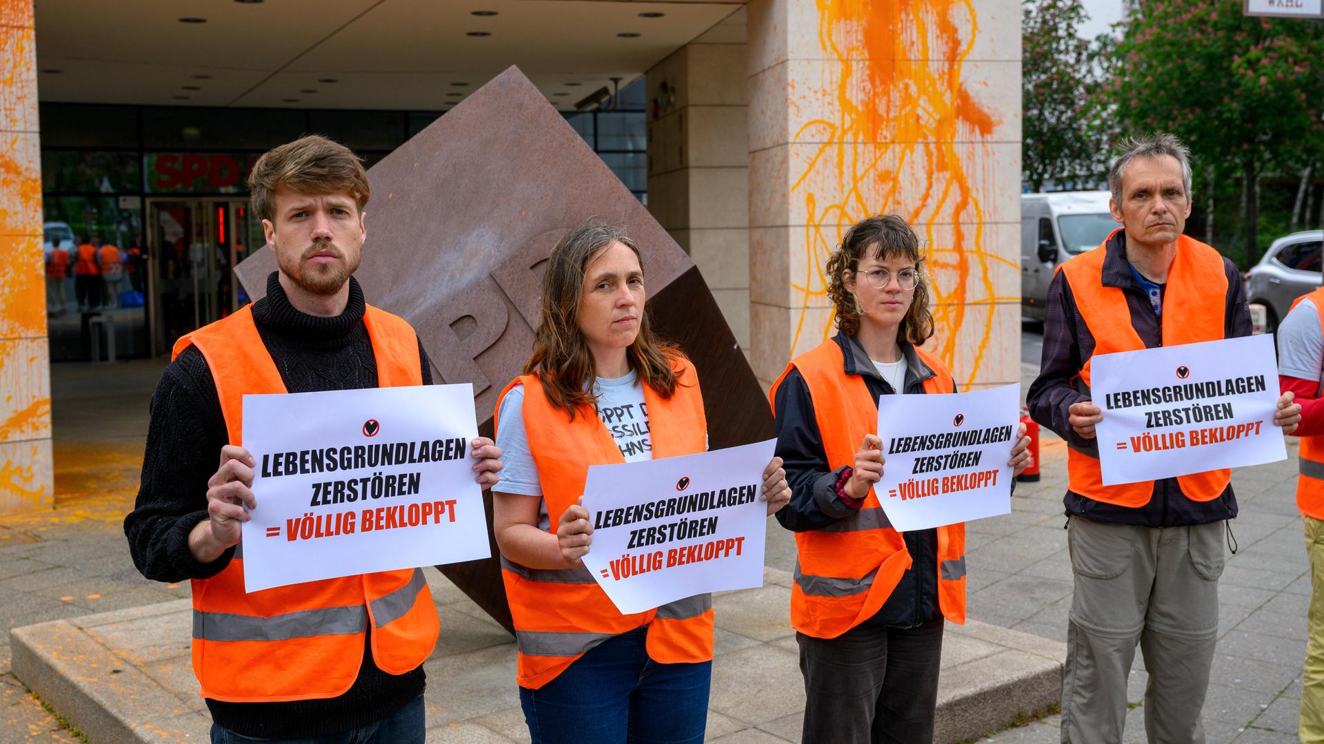 Menschen stehen mit Zetteln vor einem Gebäude.