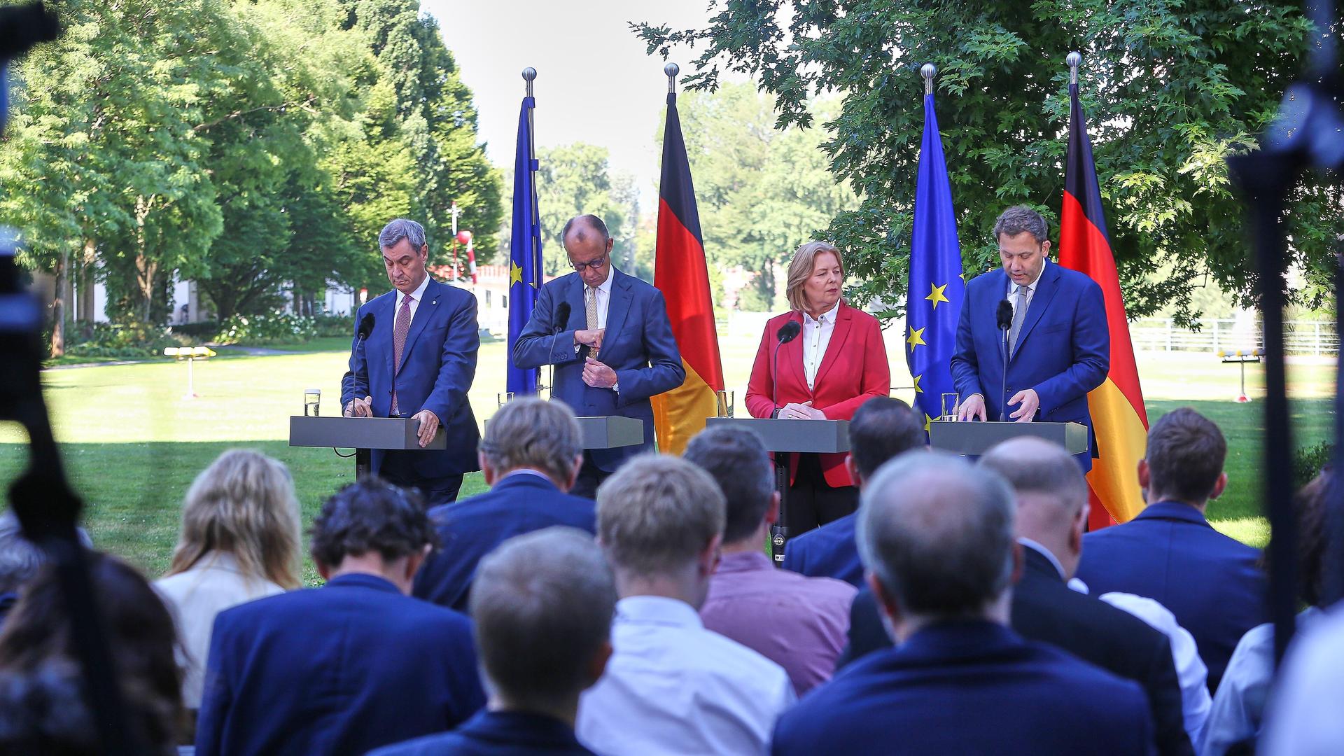 Bayerns Ministerpräsident Markus Söder (CSU), Bundeskanzler Friedrich Merz (CDU), Arbeitsministerin Bärbel Bas (SPD), Finanzminister Lars Klingbeil (SPD) stehen an vier Stehtischen im Grünen und geben eine Pressekonferenz. Bayerns Ministerpräsident Markus Söder (CSU), Bundeskanzler Friedrich Merz (CDU), Arbeitsministerin Bärbel Bas (SPD), Finanzminister Lars Klingbeil (SPD) stehen an vier Stehtischen im Grünen und geben eine Pressekonferenz.
