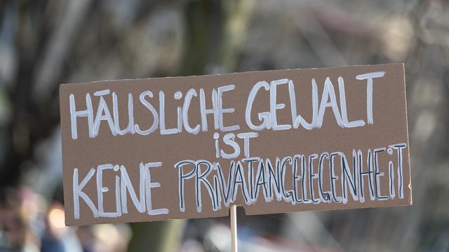 Ein Schild mit der Aufschrift „Häusliche Gewalt ist keine Privatangelegenheit“ wird auf einer Demonstration hochgehalten.