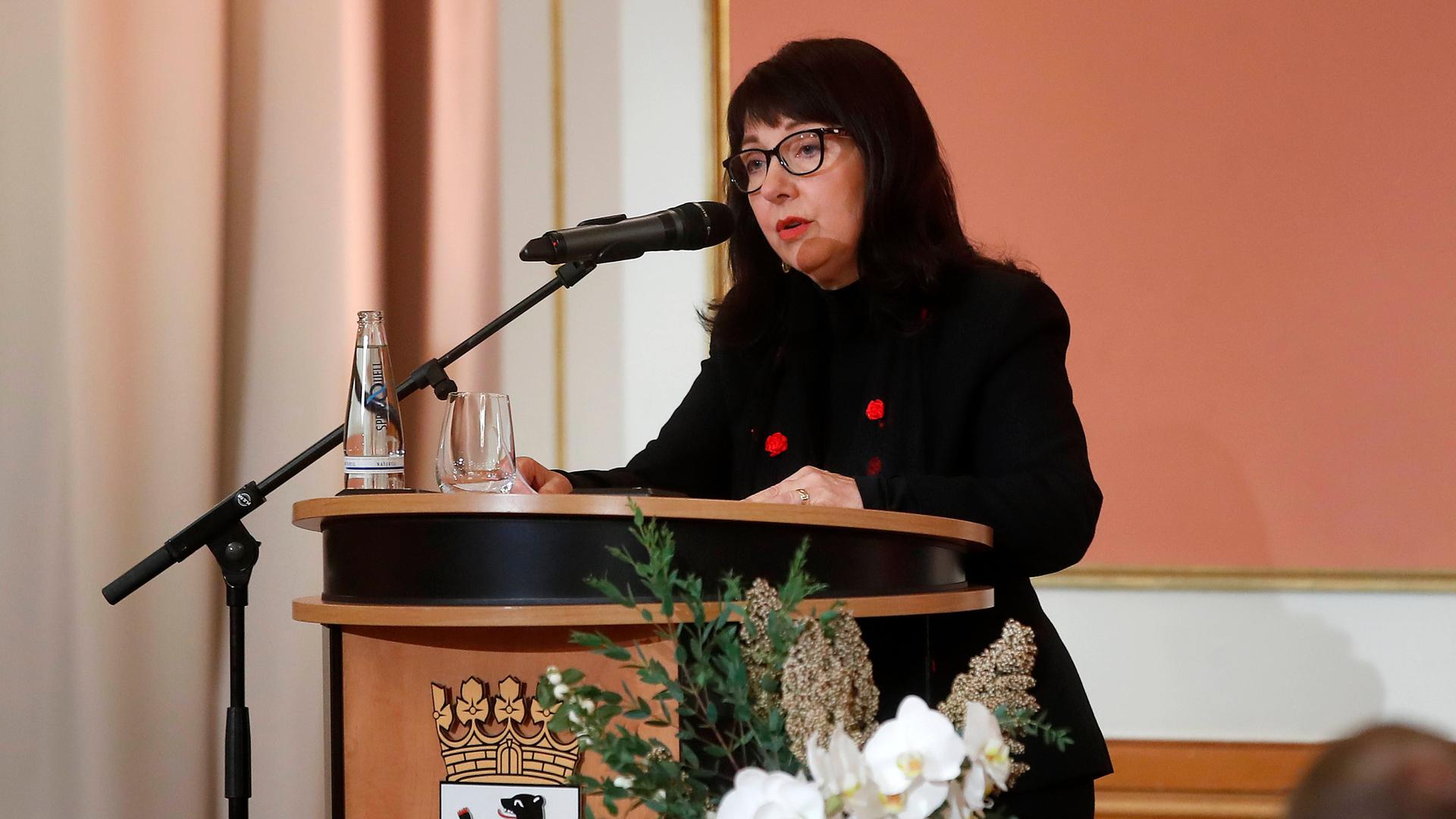 Petra Rosenberg steht an einem Pult der Stadt Berlin am Mikrofon Petra Rosenberg steht an einem Pult der Stadt Berlin am Mikrofon