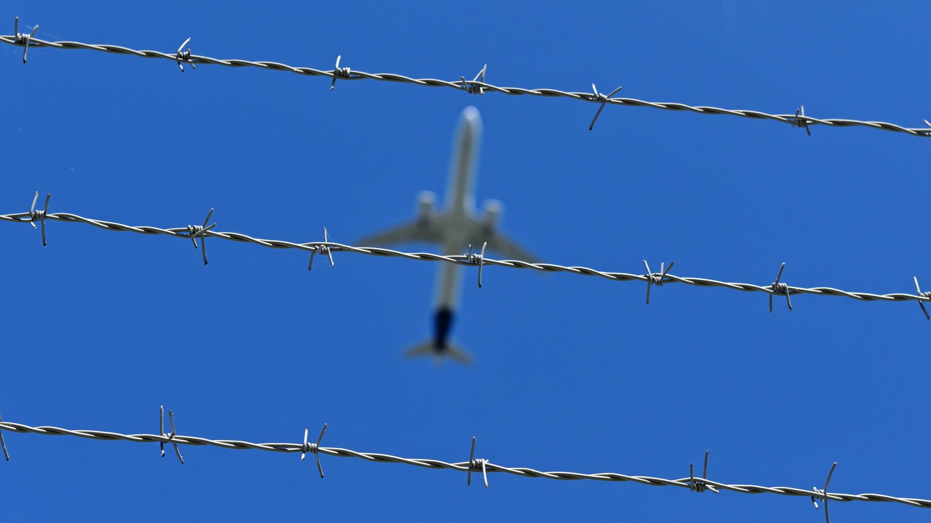 Ein Flugzeug fliegt über Stacheldraht hinweg