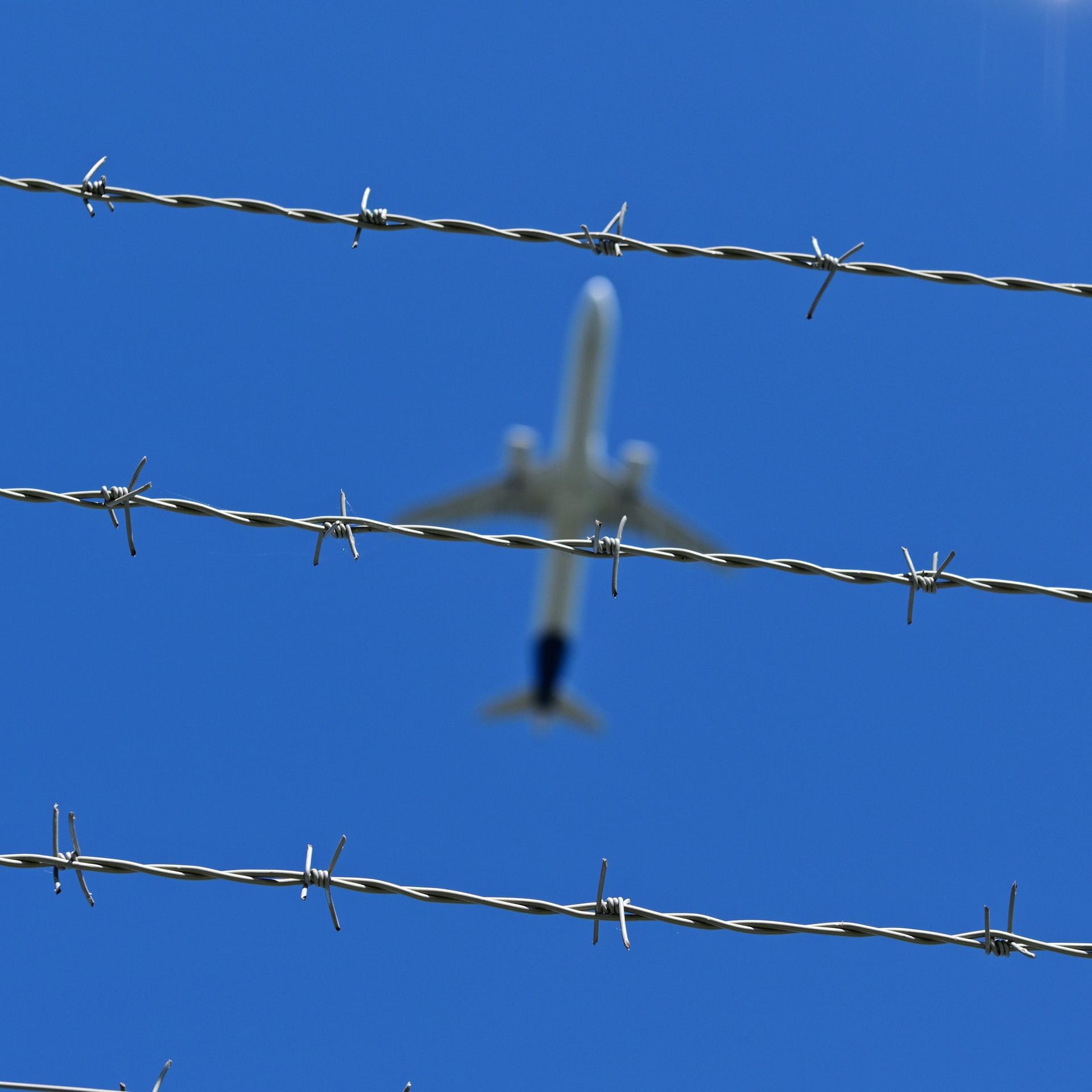 Ein Flugzeug fliegt über Stacheldraht hinweg