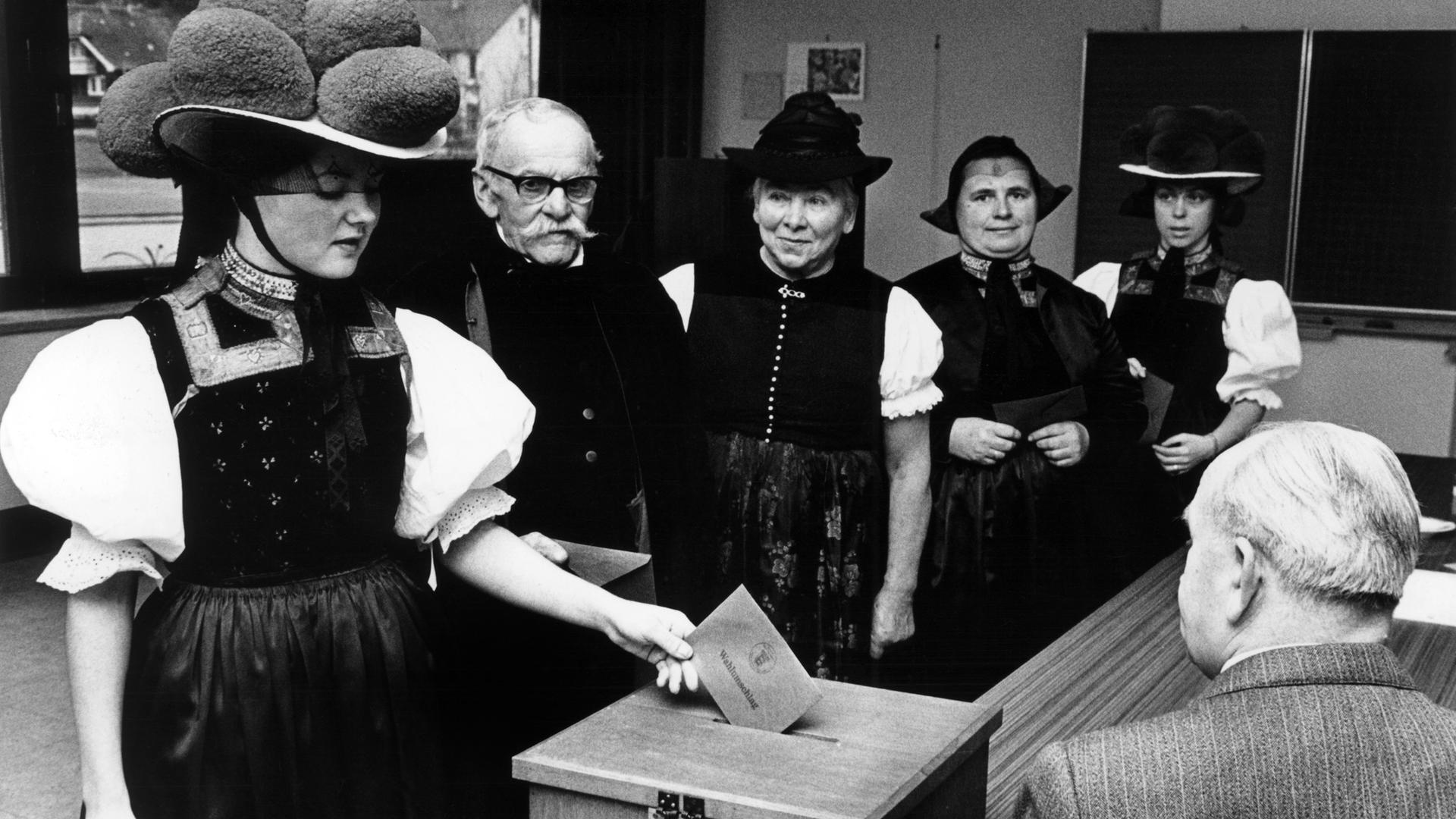 Wählerinnen und Wähler in traditionellen Trachten des Schwarzwaldes geben am 23.04.1972 bei der Landtagswahl 1972 in Baden-Württemberg in einem Wahllokal ihre Stimme ab. 