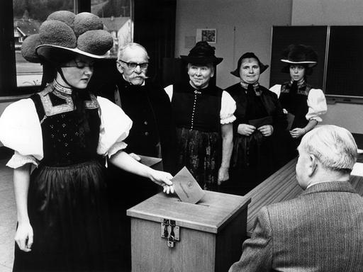 Wählerinnen und Wähler in traditionellen Trachten des Schwarzwaldes geben am 23.04.1972 bei der Landtagswahl 1972 in Baden-Württemberg in einem Wahllokal ihre Stimme ab. 