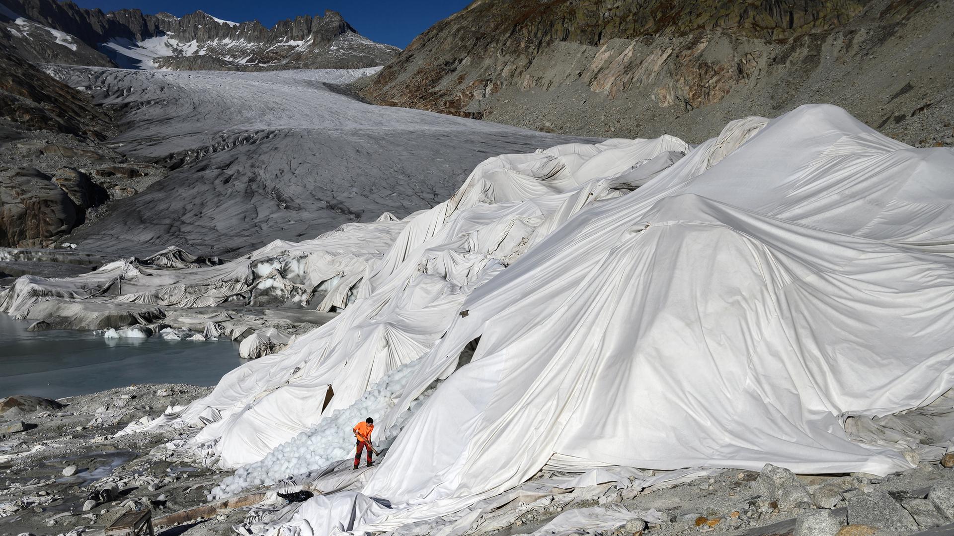 Ein Mann arbeitet am Rhonegletscher, der teilweise mit Isolierschaum bedeckt ist, um zu verhindern, dass er aufgrund der globalen Erwärmung schmilzt, 27. Oktober 2021. Ein Mann arbeitet am Rhonegletscher, der teilweise mit Isolierschaum bedeckt ist, um zu verhindern, dass er aufgrund der globalen Erwärmung schmilzt, 27. Oktober 2021.