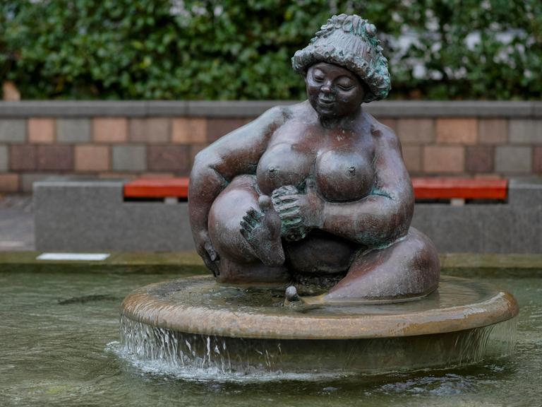 Die Brunnenfigur einer dicken nackten Frau beim Baden.