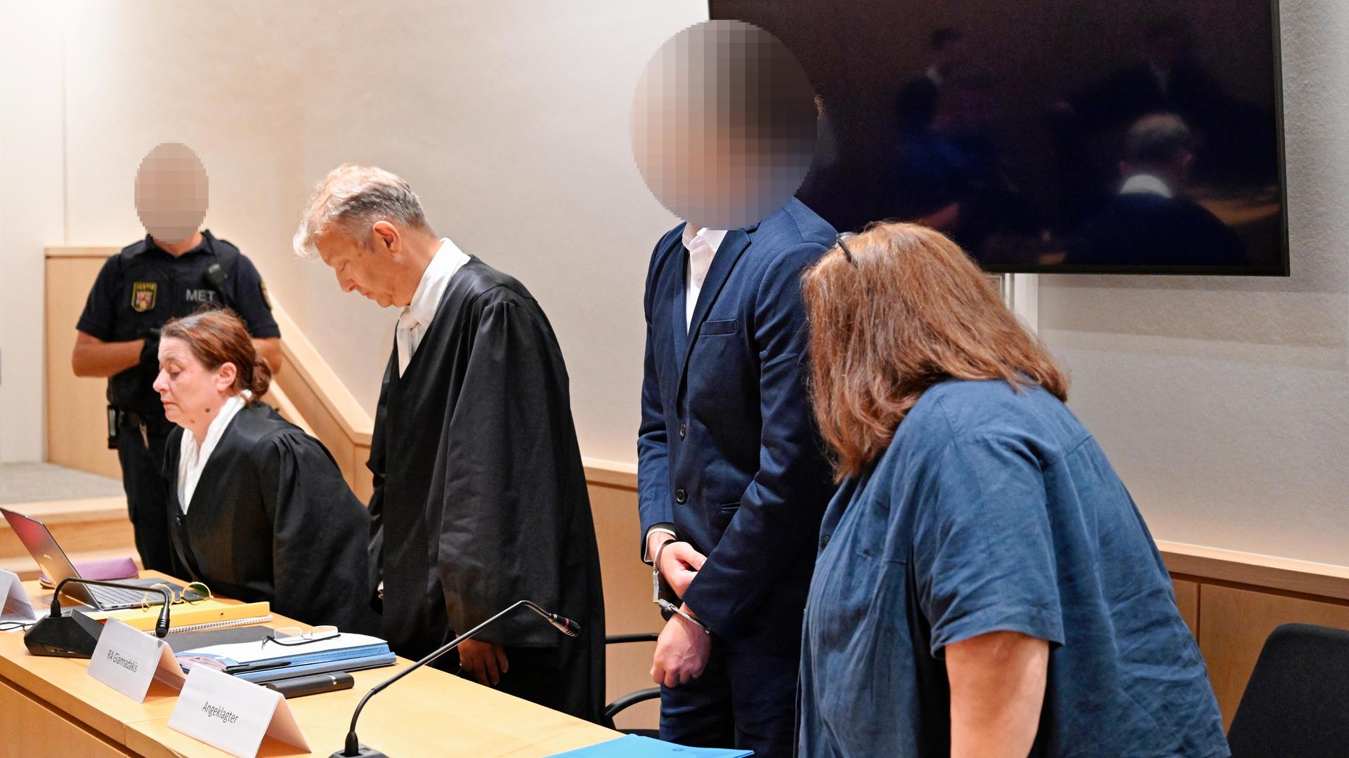 Der Angeklagte (2.v.r.) steht neben seinen Anwälten und der Dolmetscherin im Verhandlungssaal des Landgerichts. Der Angeklagte (2.v.r.) steht neben seinen Anwälten und der Dolmetscherin im Verhandlungssaal des Landgerichts.