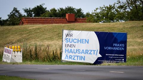 Mit einem Plakat wird in einer ländlichen Region in Schleswig-Holstein nach Ärzten und Ärztinnen gesucht. 