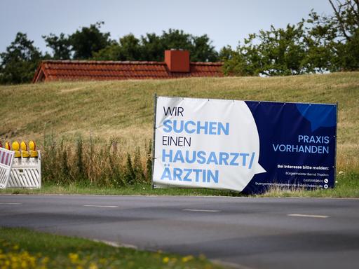 Mit einem Plakat wird in einer ländlichen Region in Schleswig-Holstein nach Ärzten und Ärztinnen gesucht. 