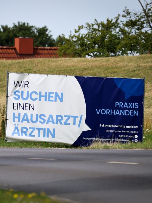 Mit einem Plakat wird in einer ländlichen Region in Schleswig-Holstein nach Ärzten und Ärztinnen gesucht. 
