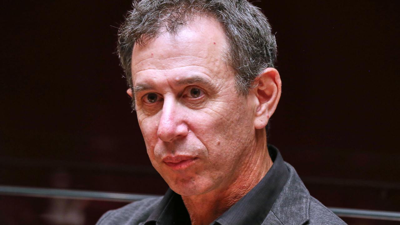 Portrait von Assaf Gavron, der vor einem dunklen Hintergrund sitzt und an der Kamera vorbeischaut. Portrait von Assaf Gavron, der vor einem dunklen Hintergrund sitzt und an der Kamera vorbeischaut.