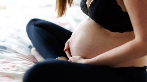 Eine schwangere Frau hält ihren Bauch