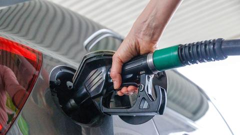 Autofahrer beim Betanken an der Zapfsäule einer Tankstelle.