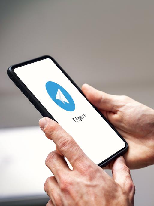 Ein Smartphone mit Telegram-Logo, das in Händen gehalten wird