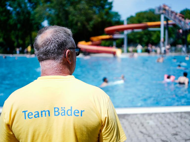 Ein Bademeister steht im Herzogenriedbad vor einem Schwimmbecken mit Wasserrutsche.