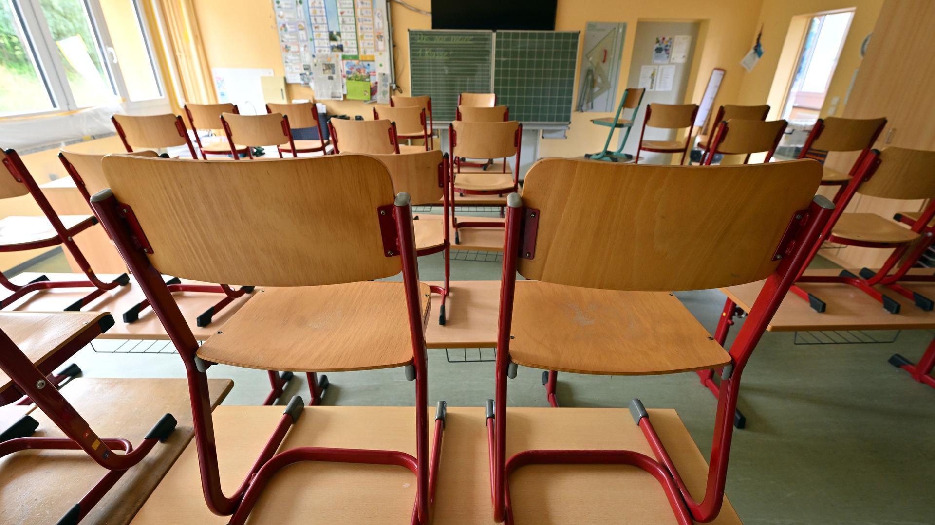 In einem leeren Klassenzimmer stehen Stühle auf den Tischen.