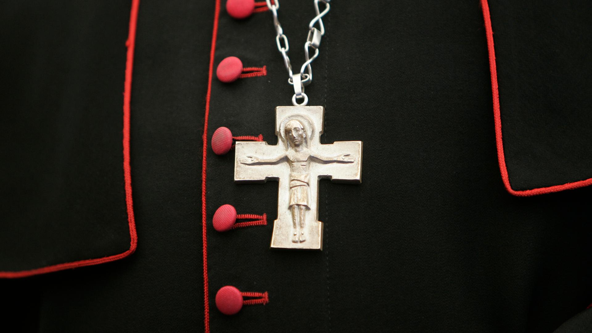 Ein Kreuz hängt an einer Kette über dem Bischofsgewand.