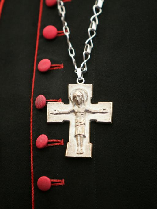 Ein Kreuz hängt an einer Kette über dem Bischofsgewand.
