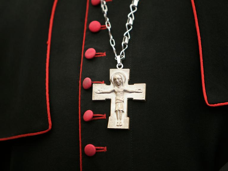 Ein Kreuz hängt an einer Kette über dem Bischofsgewand.