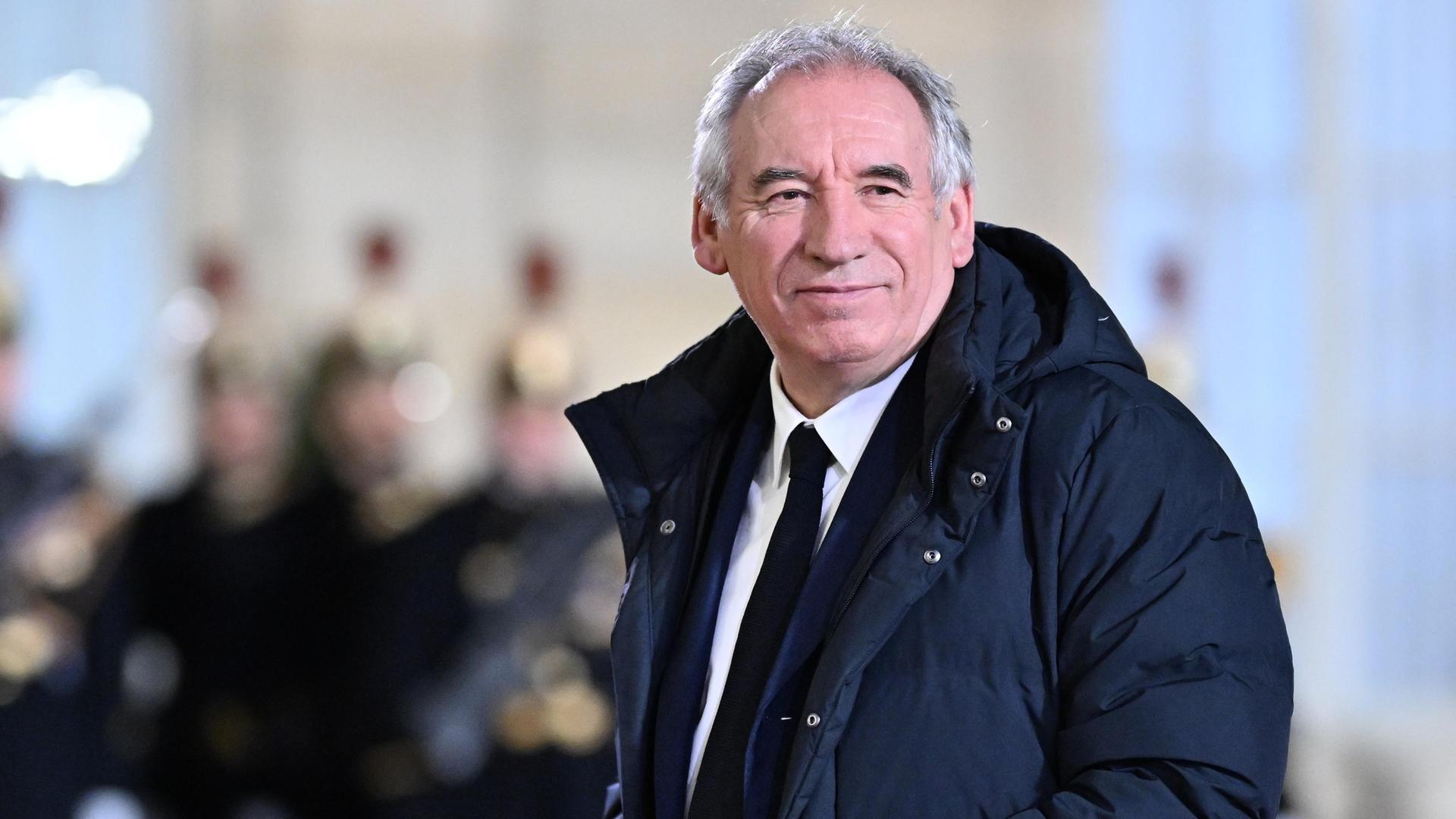 Frankreichs Premierminister Francois Bayrou trägt einen langen Daunenanorak und guckt in die Kamera.