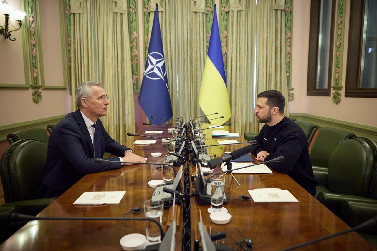 Nato-Generalsekretär Stoltenberg sitzt dem ukrainischen Präsidenten Selenskyj an einem Konferenztisch gegenüber. Hinter den beiden sind die Fahnen der Nato und der Ukraine.