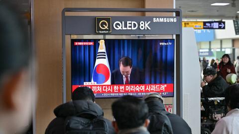 Das Foto zeigt Menschen, die auf einem Bildschirm eine Rede von Südkoreas Präsident Yoon verfolgen.