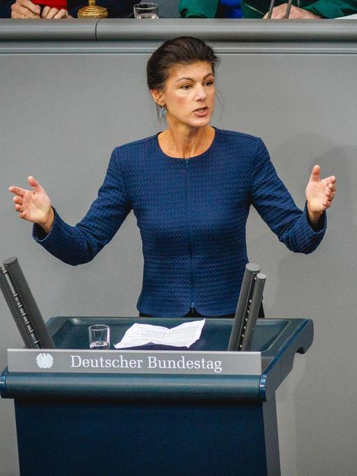 Sahra Wagenknecht steht hinter einem Rednerpult im Bundestag und breitet die Hände aus.