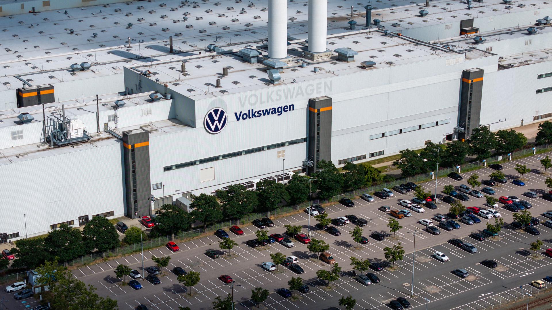 Luftaufnahme eines Werks von Volkswagen mit dem Firmenlogo auf dem Dach und einem großen vorgelagerten Parkplatz. Luftaufnahme eines Werks von Volkswagen mit dem Firmenlogo auf dem Dach und einem großen vorgelagerten Parkplatz.