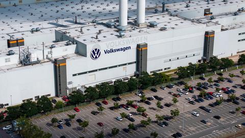Luftaufnahme eines Werks von Volkswagen mit dem Firmenlogo auf dem Dach und einem großen vorgelagerten Parkplatz.