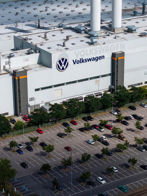 Luftaufnahme eines Werks von Volkswagen mit dem Firmenlogo auf dem Dach und einem großen vorgelagerten Parkplatz. Luftaufnahme eines Werks von Volkswagen mit dem Firmenlogo auf dem Dach und einem großen vorgelagerten Parkplatz.