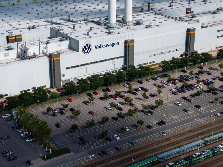 Luftaufnahme eines Werks von Volkswagen mit dem Firmenlogo auf dem Dach und einem großen vorgelagerten Parkplatz. Luftaufnahme eines Werks von Volkswagen mit dem Firmenlogo auf dem Dach und einem großen vorgelagerten Parkplatz.