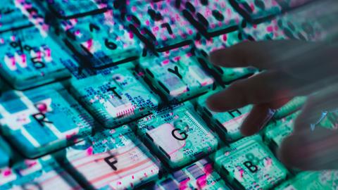 Hände tippen auf einer Computertastatur. Unter der Tastatur ist die Computerhardware zu sehen.