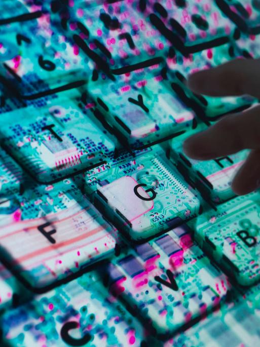 Hände tippen auf einer Computertastatur. Unter der Tastatur ist die Computerhardware zu sehen.
