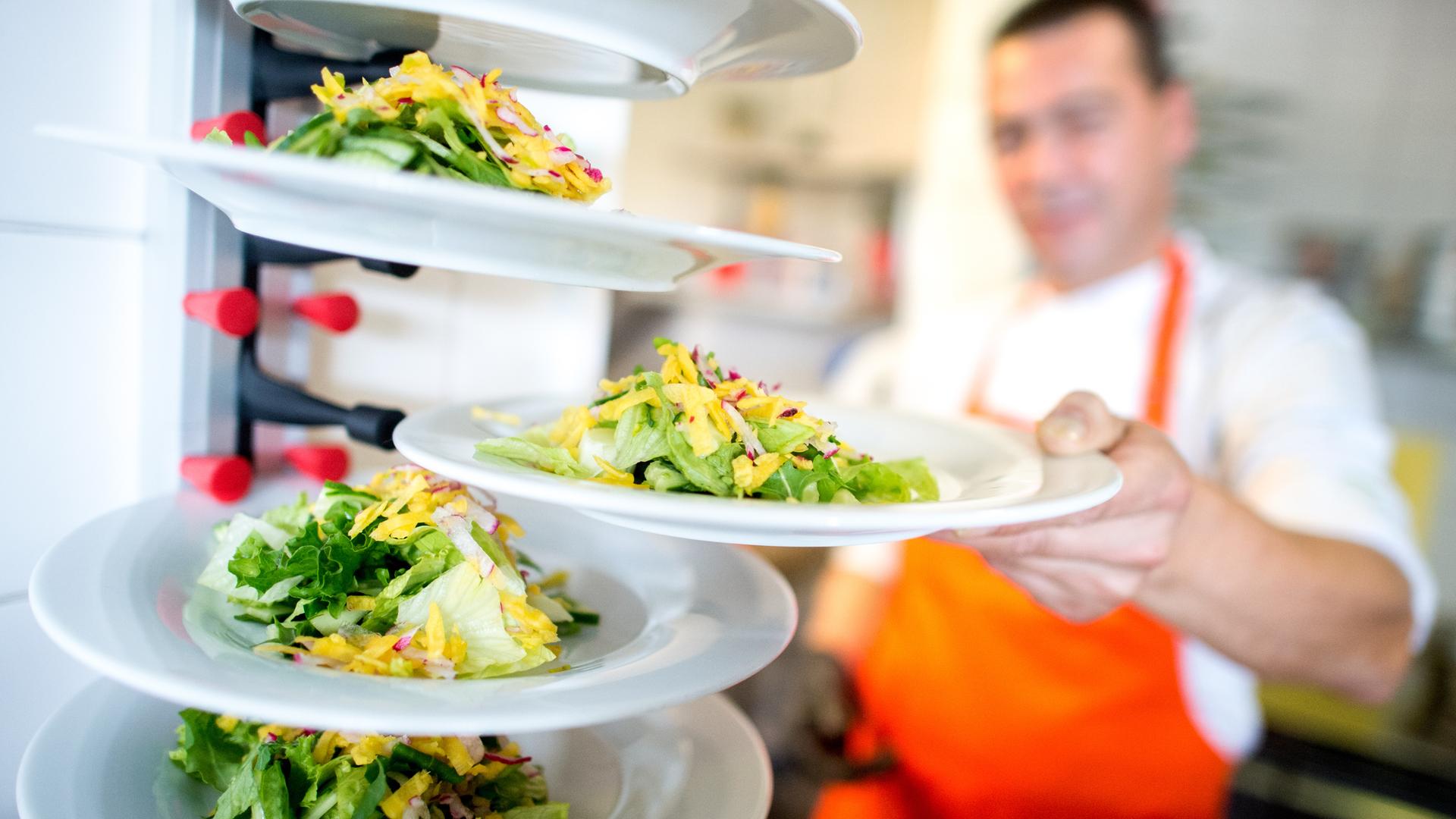 Ein Mitarbeiter bereitet im Betriebsrestaurant die Salatbeilage eines Tellergerichts vor. 